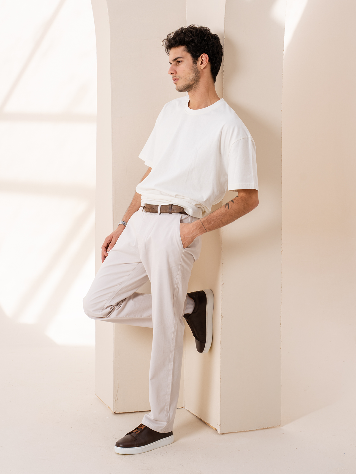 A man in a CLOUD white tee and light trousers